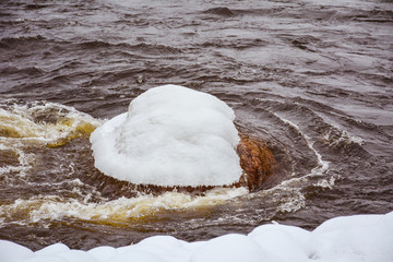 Big stone in the water in a snow hat