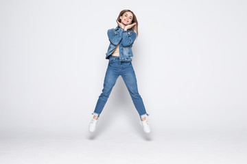 Full length portrait of a cheerful young woman jumping and celebrating over gray background