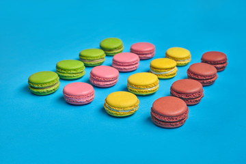 Colored macaron or macaroon, sweet meringue-based confection on blue background. Close-up, copy space.