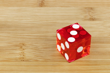 Red glass glass classic dice on a bamboo background. Fallen troika, selective focus.