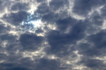 Obraz premium Through dense dark clouds, a bright sun breaks through without visible rays, a natural background.