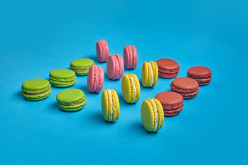 Colored macaron or macaroon, sweet meringue-based confection on blue background. Close-up, copy space.