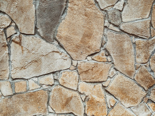 Imitation of a wild stone. Wall decorated with ocher stone tiles. The effect of the fortress. Close up, copy space.