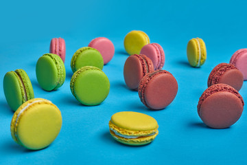Colored macaron or macaroon, sweet meringue-based confection on blue background. Close-up, copy space.