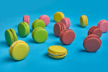 Colored macaron or macaroon, sweet meringue-based confection on blue background. Close-up, copy space.