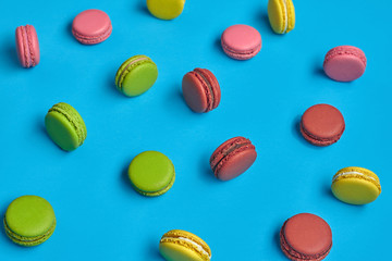 Obraz premium Colored macaron or macaroon, sweet meringue-based confection on blue background. Close-up, copy space.
