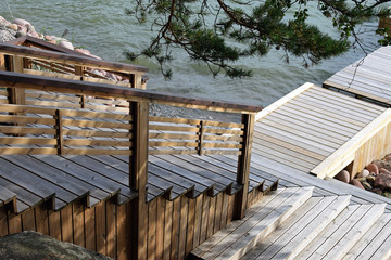 Wooden stairs leading to swimming pier. Beach in cottage on summer day.