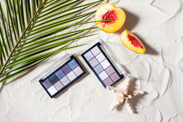 Charming beach. Palette of shadows with square refills surrounded by corals, and palm leaves lie on...