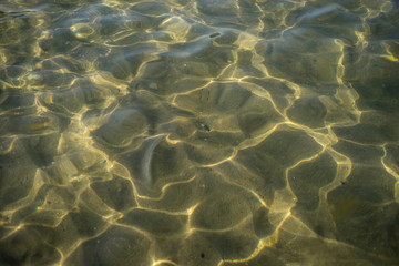 Water edge ripples reflection on the shallow sandy bottom under the sun light in the Black Sea.