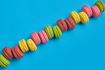 Colored macaron or macaroon, sweet meringue-based confection on blue background. Close-up, copy space.