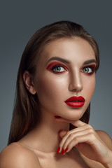 Fototapeta premium Close-up glamour portrait of a beautiful half-naked model with bright make-up posing over a gray background.