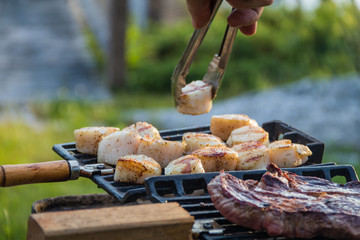 Steak and Scallops grilling on a hibachi as hot charcoal develops smoke and flames on a summer night