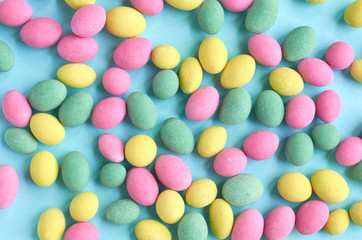 Colored sweets, peanut covered with glaze on blue background composition.