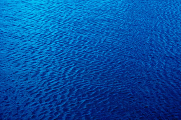 Fototapeta na wymiar Shining dark blue wavy water surface ripple background