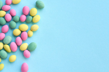 Colored sweets, peanut covered with glaze on blue background composition.