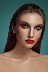 Close-up glamour portrait of a beautiful half-naked model with bright make-up posing over a gray background.