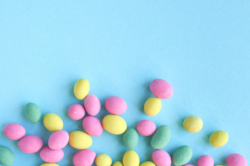 Colored sweets, peanut covered with glaze on blue background composition.