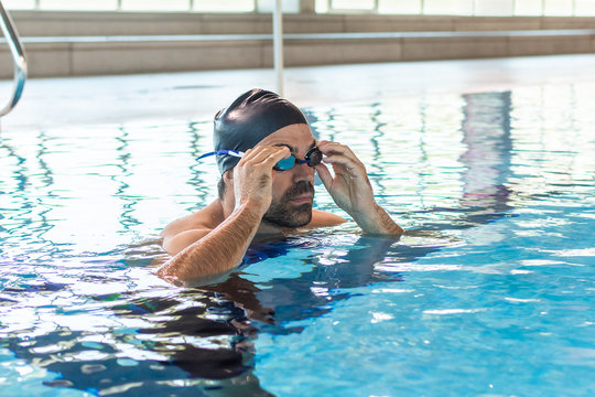 Young male swimmer adjusting his goggles for swimming in olympic pool