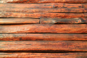 Horizontal red brown wood log outer wall of an aging log cabin for background or banner