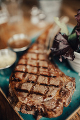 A close up shot of a beef steak served on the green plate with salad and sauces. Concept of restaurant, food and culinary.