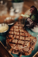 A close up shot of a beef steak served on the green plate with salad and sauces. Concept of restaurant, food and culinary.