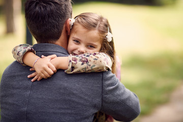 schoolgirl hugging father after school