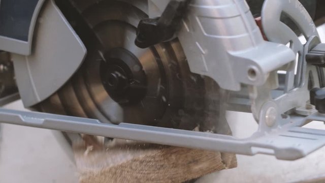 Hand man sawed wooden board using a miter saw. Chop saw.