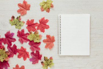 Naklejka na ściany i meble Top view autumn leaves with a notebook
