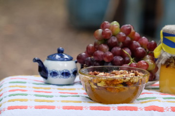 Apiculture, healthy products, organic food, beekeeping, herbal tea in the teapot, fresh honey with nuts in the bowl, grapes on wooden background, healthy lifestyle, rustic background