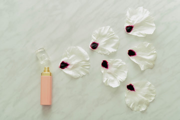  Bottle of perfume with flower petals on marble background, top view. Perfumery and floral scent concept. Spray of peony flower petals. creative trendy flat lay.