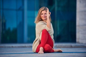 Beautiful young woman practices yoga asana Gomukhasana - Cow Face pose outdoors against the...