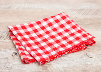  Red checkered tablecloth folded in two on a wooden table