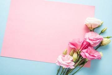 Eustoma flowers and blank note paper on light blue background