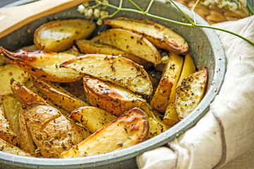 Oven baked potato in the oven with peel and spices in a baking dish. View from above. Potato wedges in peel, homemade lunch concept, dish with potatoes, baked potato recipe, Rustic potato
