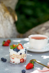 Granola in glass with berries and tea