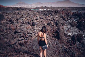 Chica Caminando de espaldas por paisaje volcánico en la isla de Lanzarote