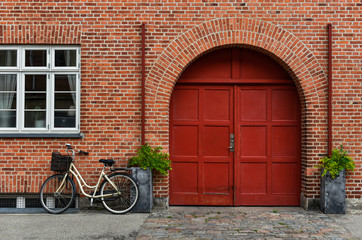 Fototapeta na wymiar classic bicycle with basket parked near old brick house with wooden gate