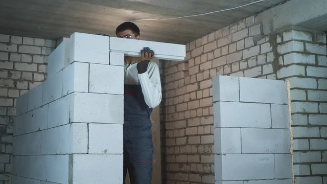 construction worker building doorway with aerated concrete blocks