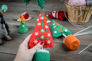 Knitted Christmas gifts handmade. Wooden background. Making knit New Year decoration. Christmas ornaments.