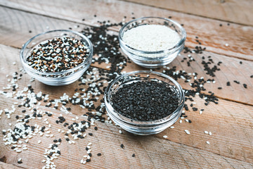 Different types of sesame seeds. White, black and multi-colored sesame seeds. Seasonings on a wooden background.