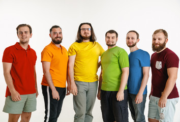 Young men weared in LGBT flag colors isolated on white background. Caucasian male models in shirts of red, orange, yellow, green, blue and purple. LGBT pride, human rights and choice concept.