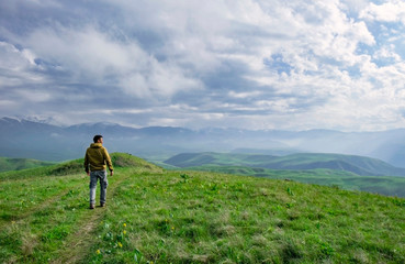 Obraz premium Beautiful landscape, man standing on the hill in front of mountains