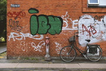 not locked classic bicycle with basket near the wall with graffiti
