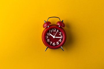 Red alarm clock on yellow background