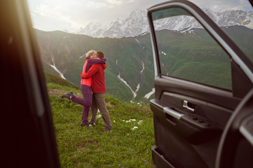 Happy couple hugs on beautiful nature and mountains out of car 