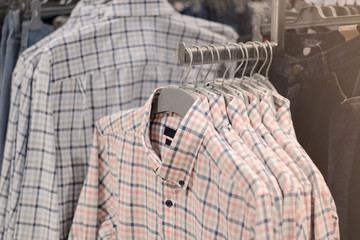 Clothes on hangers in store. Mens shirts hang on clothing rack. Shopping time concept
