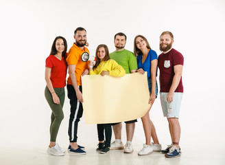 Young man and woman weared in LGBT flag colors on white background. Caucasian models in bright...