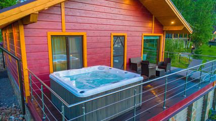 Hot tub at the house?s balkony. SPA treatments in a country cottage. Whirlpool bath in a wooden...