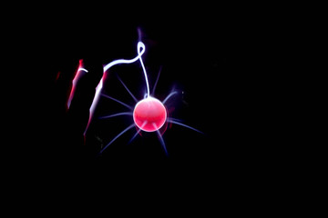 Plasma ball lamp and human hand in the darkness