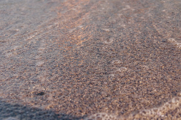 Fototapeta na wymiar Closeup of sandy beach with soft incoming waves. Selective focus